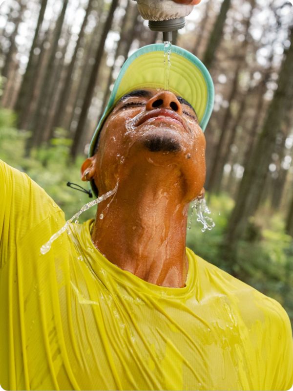 Person pouring water on themselves wearing HOKA apparel.