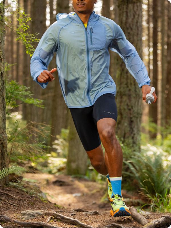 Person running in the forest wearing HOKA apparel and shoes.